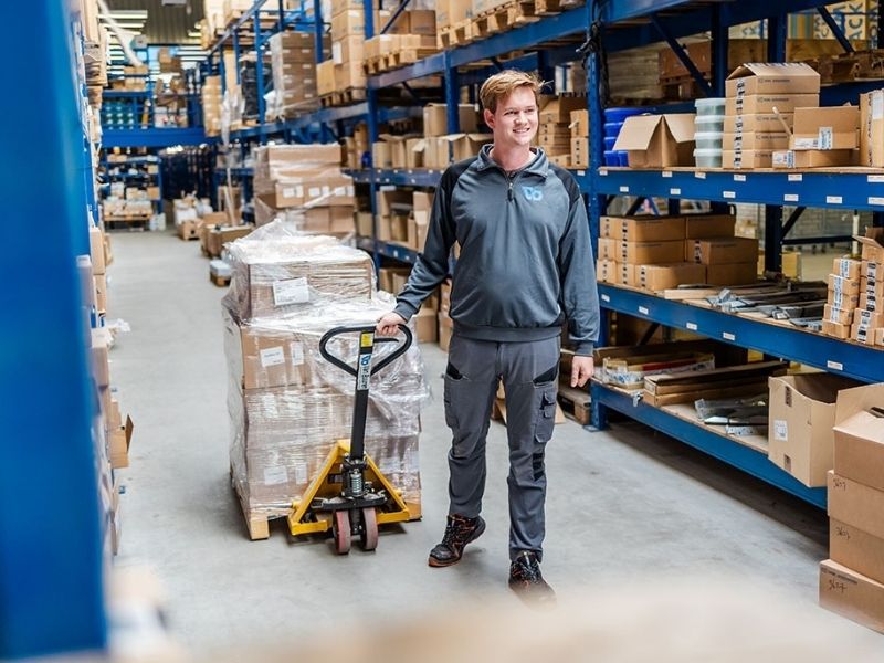 Logistiek medewerker vervoert goederen in Van Buuren magazijn vol bouwmaterialen